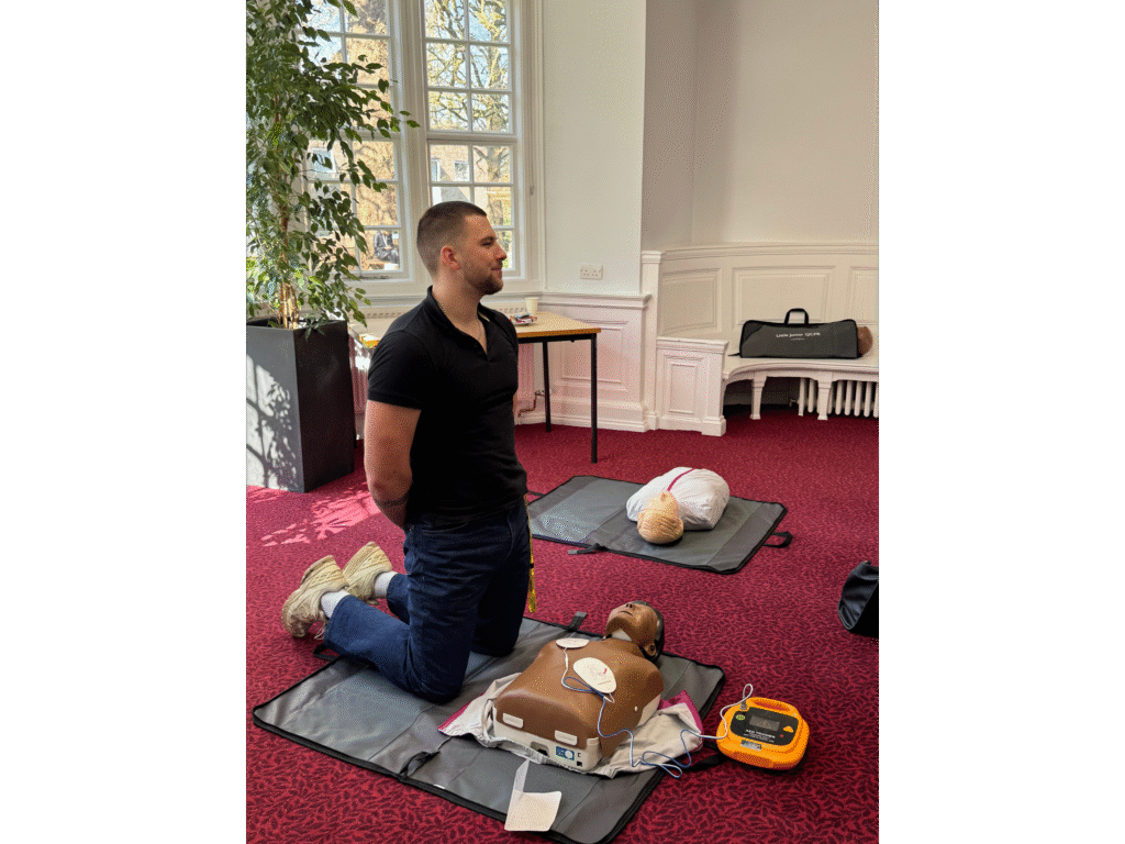 Participant practising with a CPR manikin and training defibrillator at a previous training event