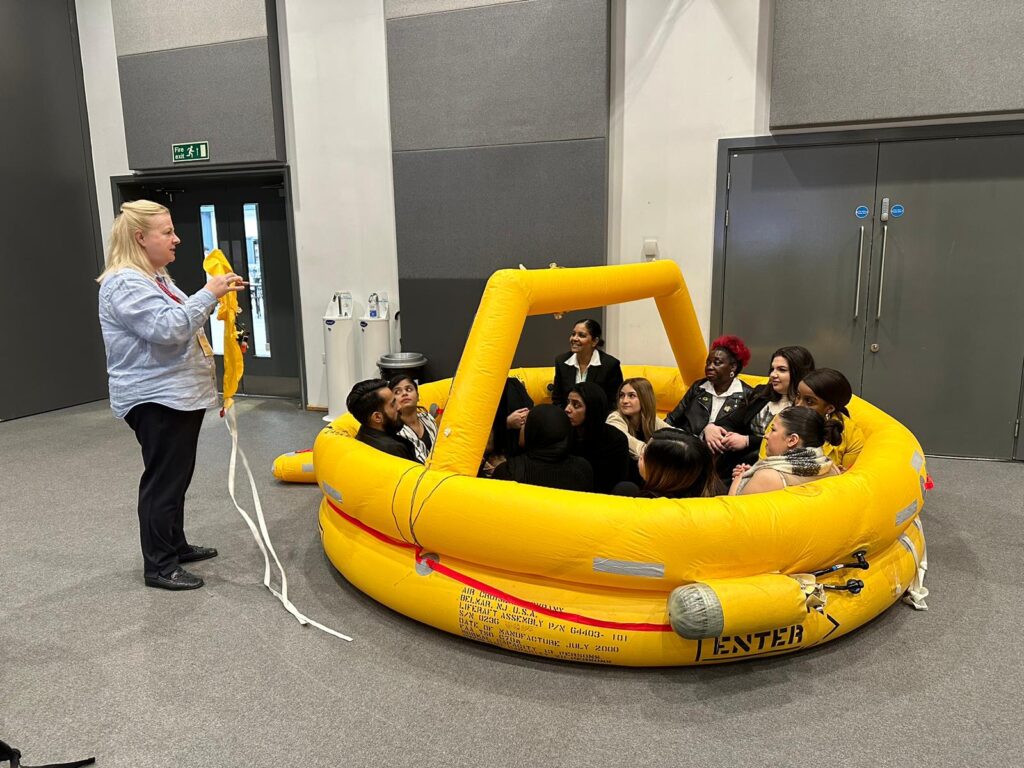 Trainees in an inflatable life raft listening to an instructor at a previous cabin crew event